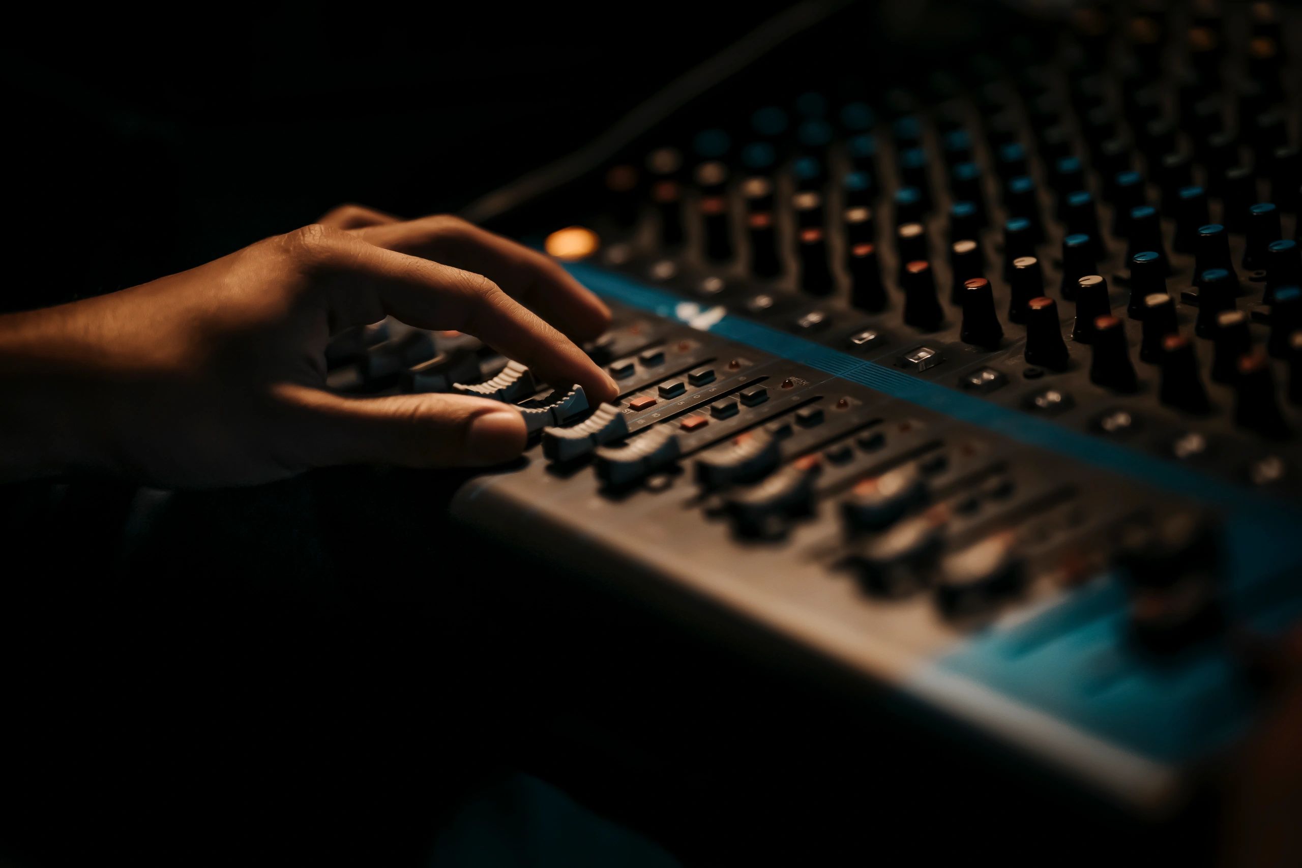 Hands adjusting audio controls on a mixing console